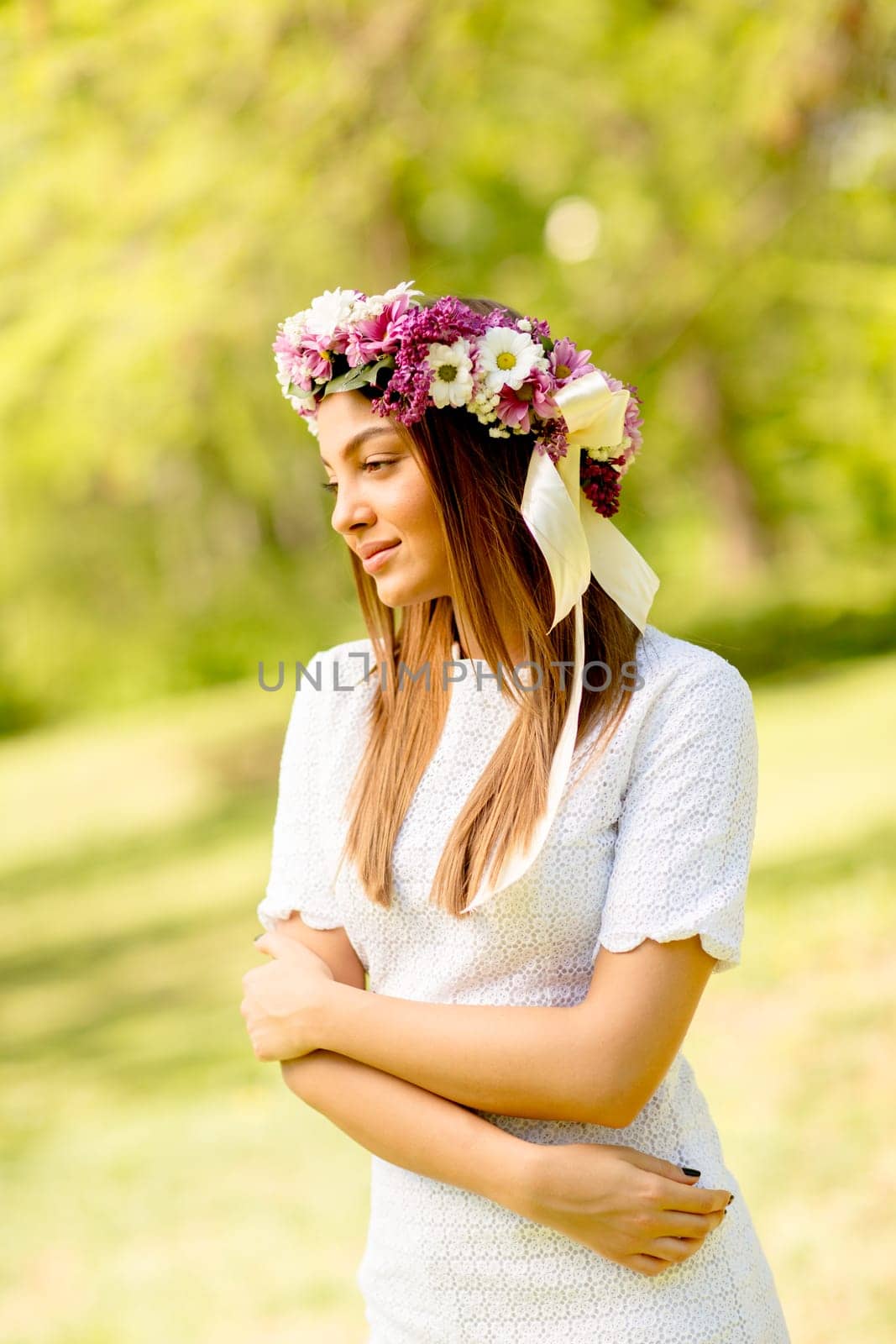Portrait of young woman with wreath of fresh flowers on head in the park