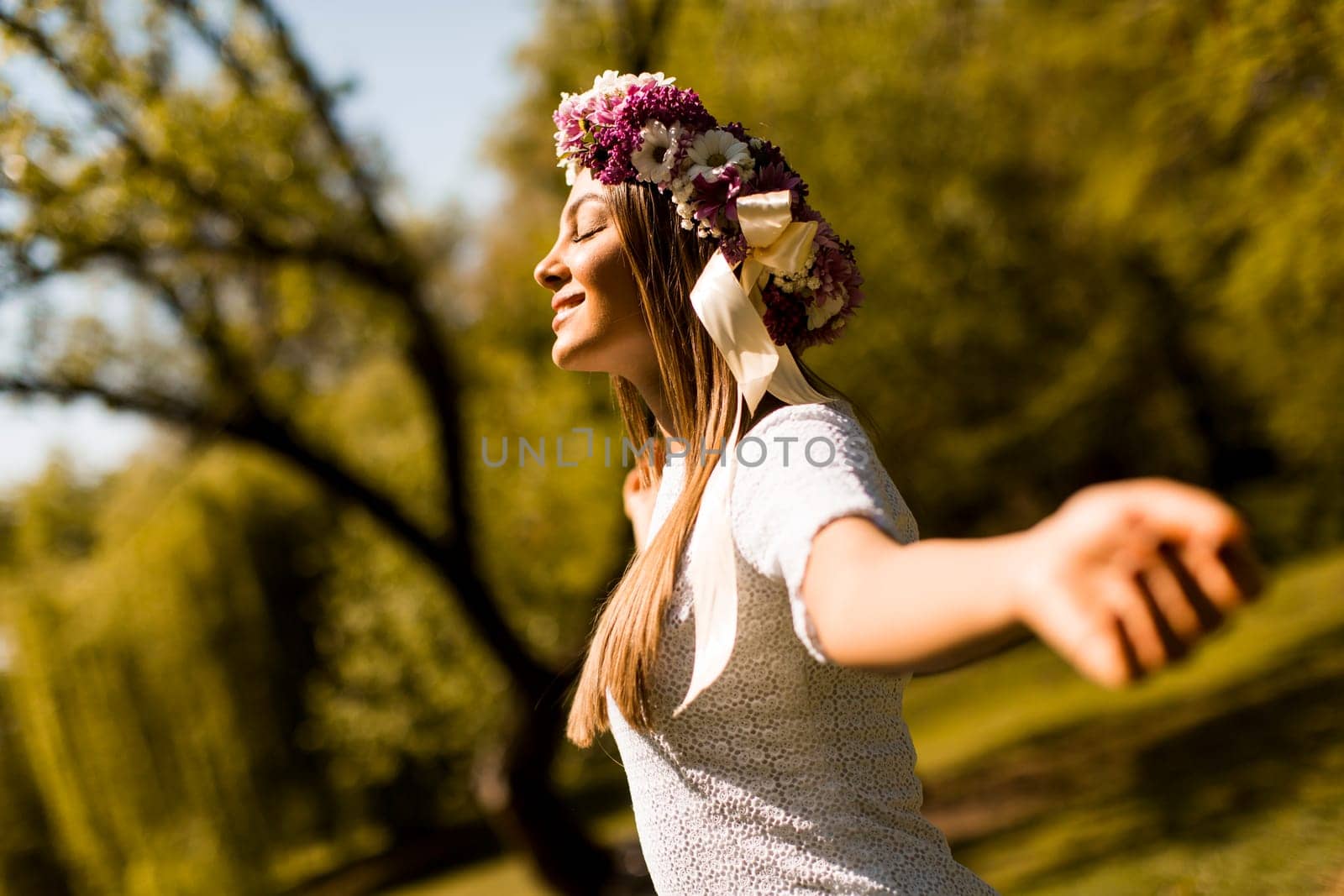 Pretty young woman with flowers in her hair on sunny spring day