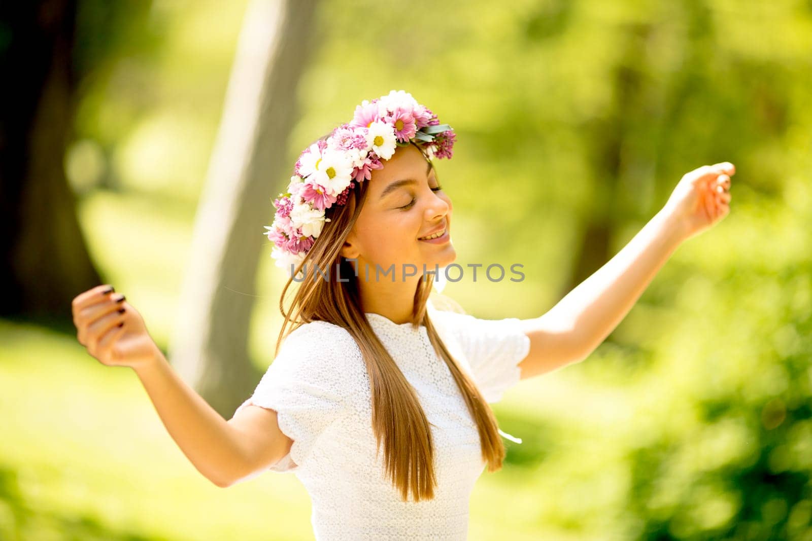 Portrait of young woman with wreath of fresh flowers on head in the park