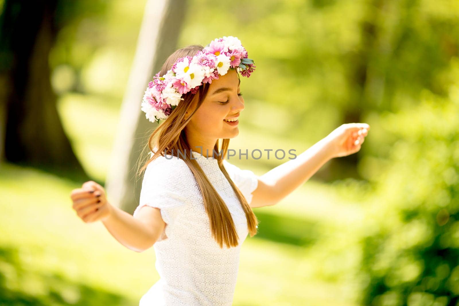 Portrait of young woman with wreath of fresh flowers on head in the park
