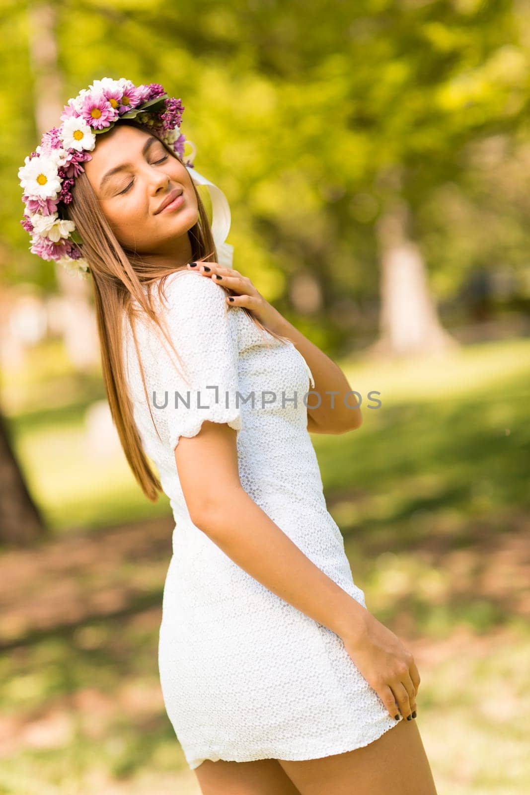 Pretty young woman with flowers in her hair on sunny spring day