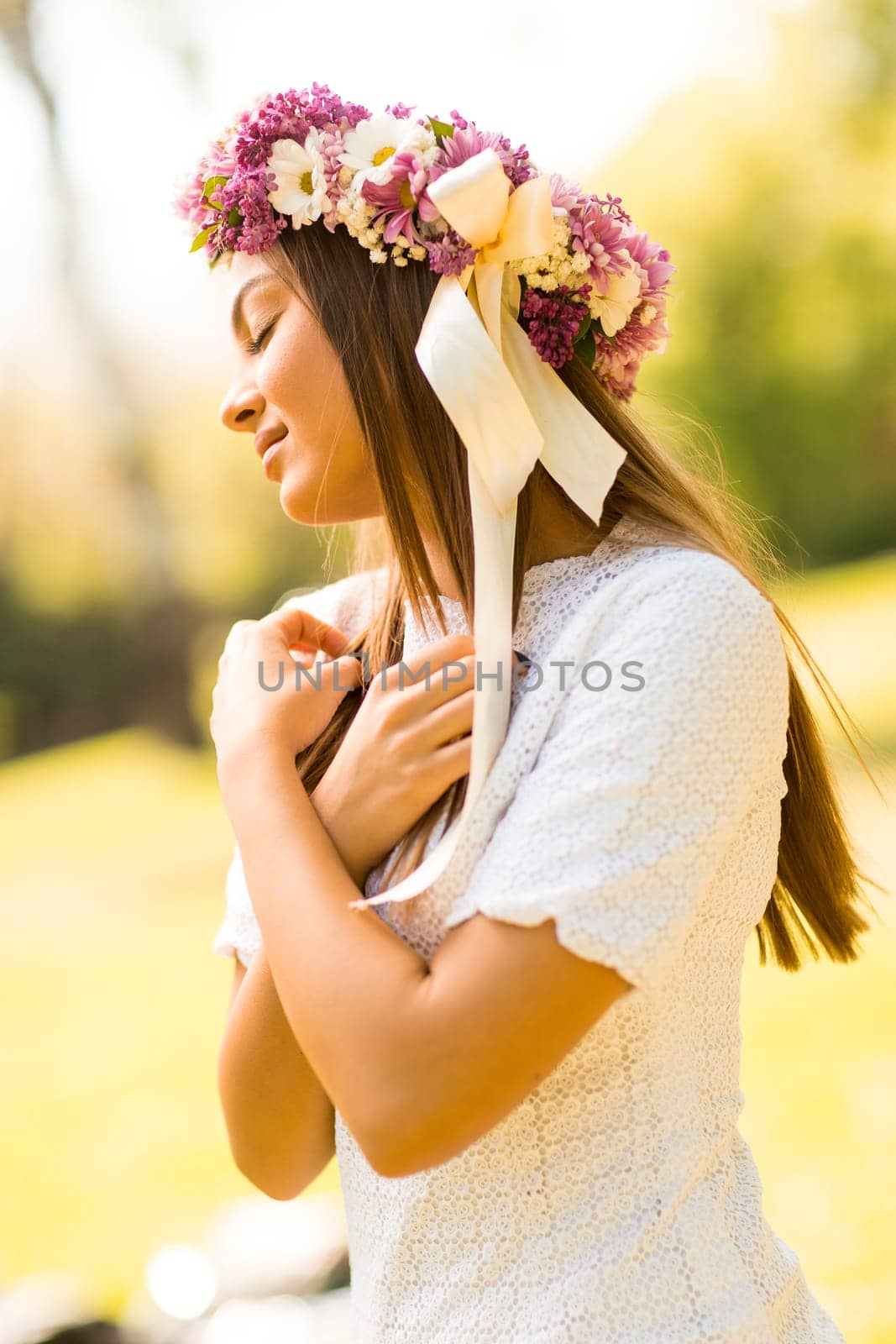 Pretty young woman with flowers in her hair on sunny spring day