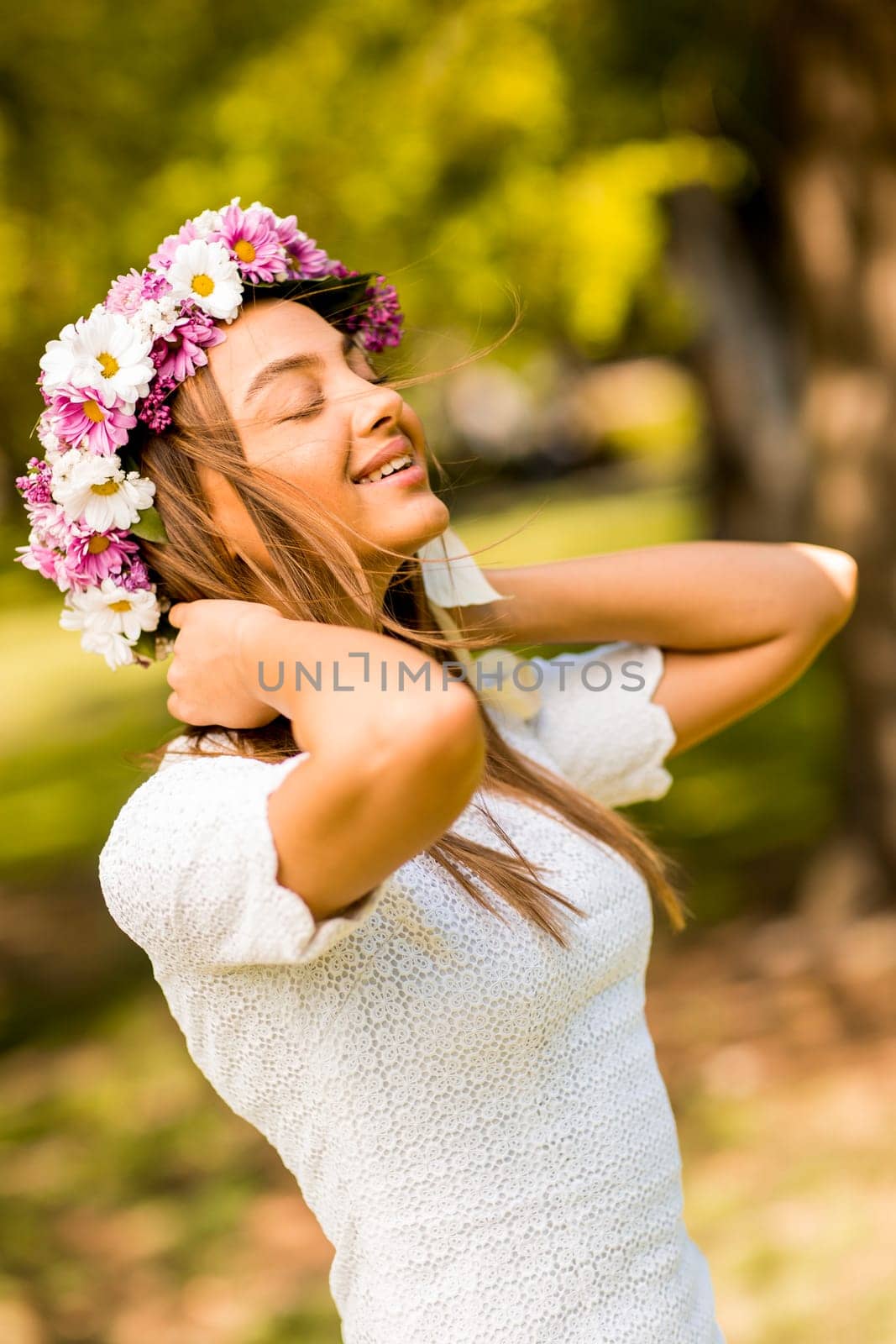 Pretty young woman with flowers in her hair on sunny spring day