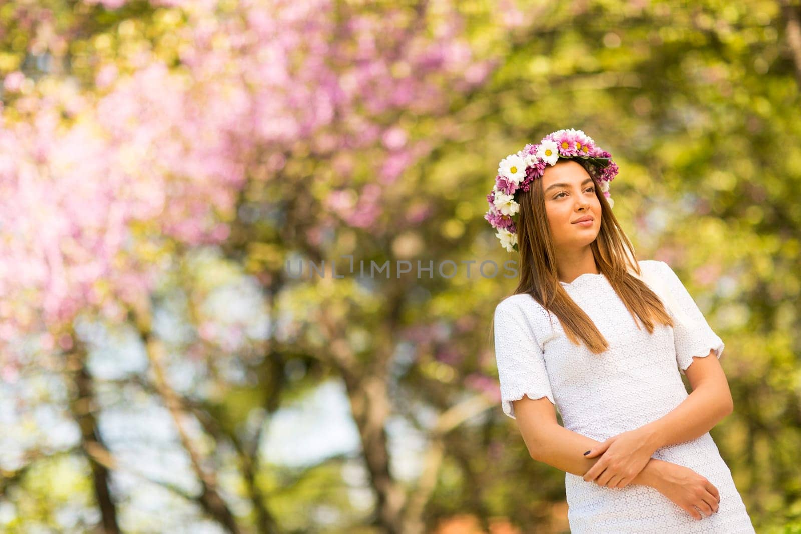Pretty young woman with flowers in her hair on sunny spring day