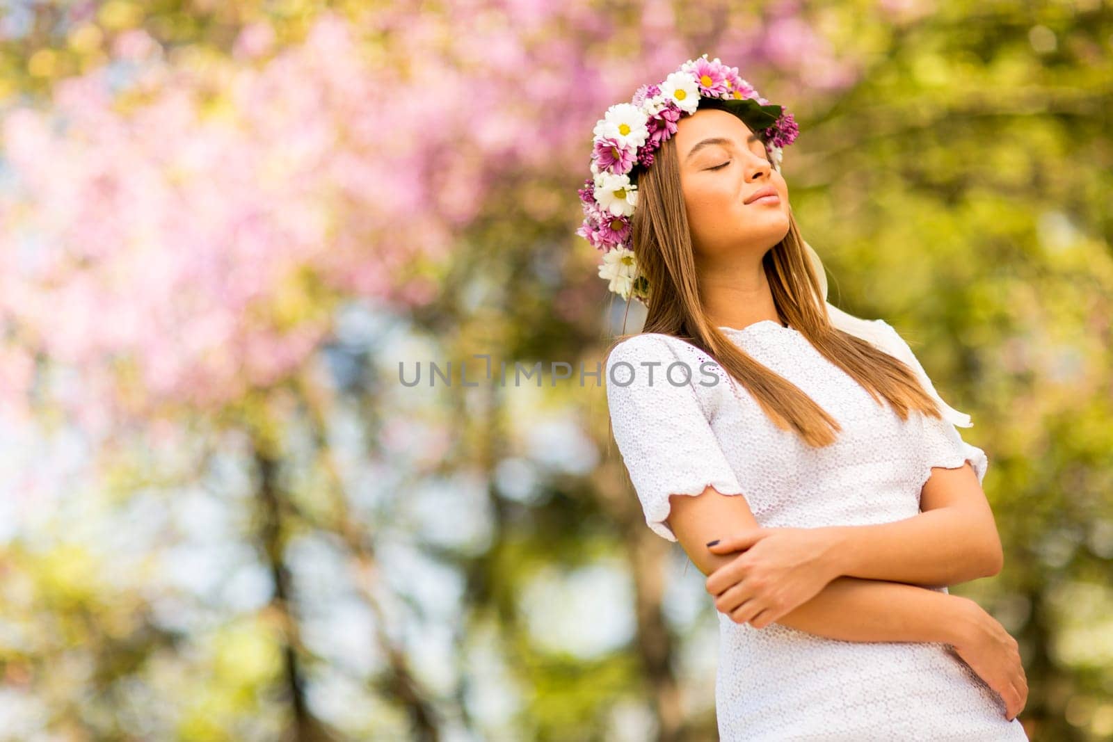 Pretty young woman with flowers in her hair on sunny spring day