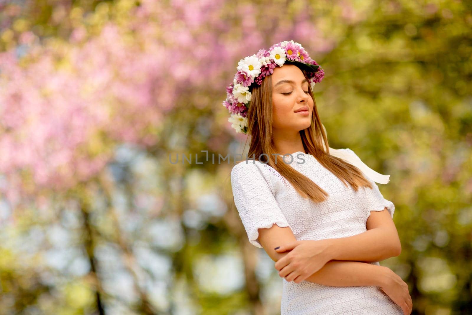 Portrait of young woman with wreath of fresh flowers on head in the park