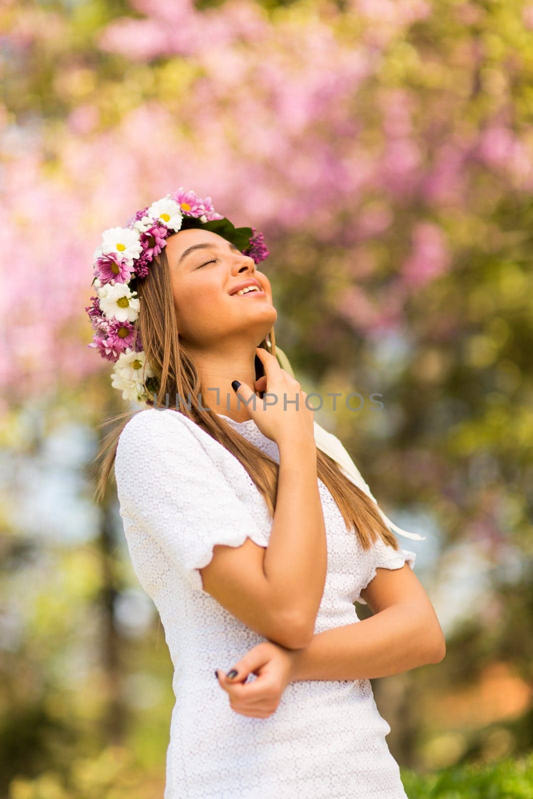 Pretty young woman with flowers in her hair on sunny spring day
