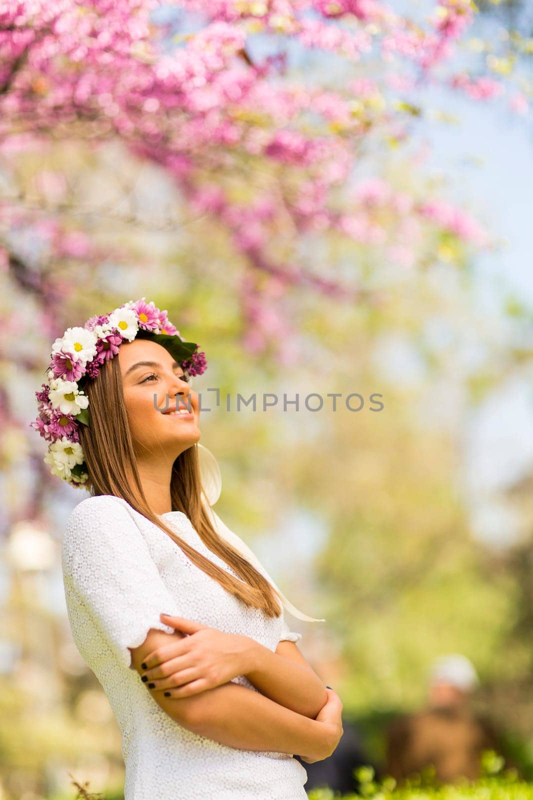 Pretty young woman with flowers in her hair on sunny spring day