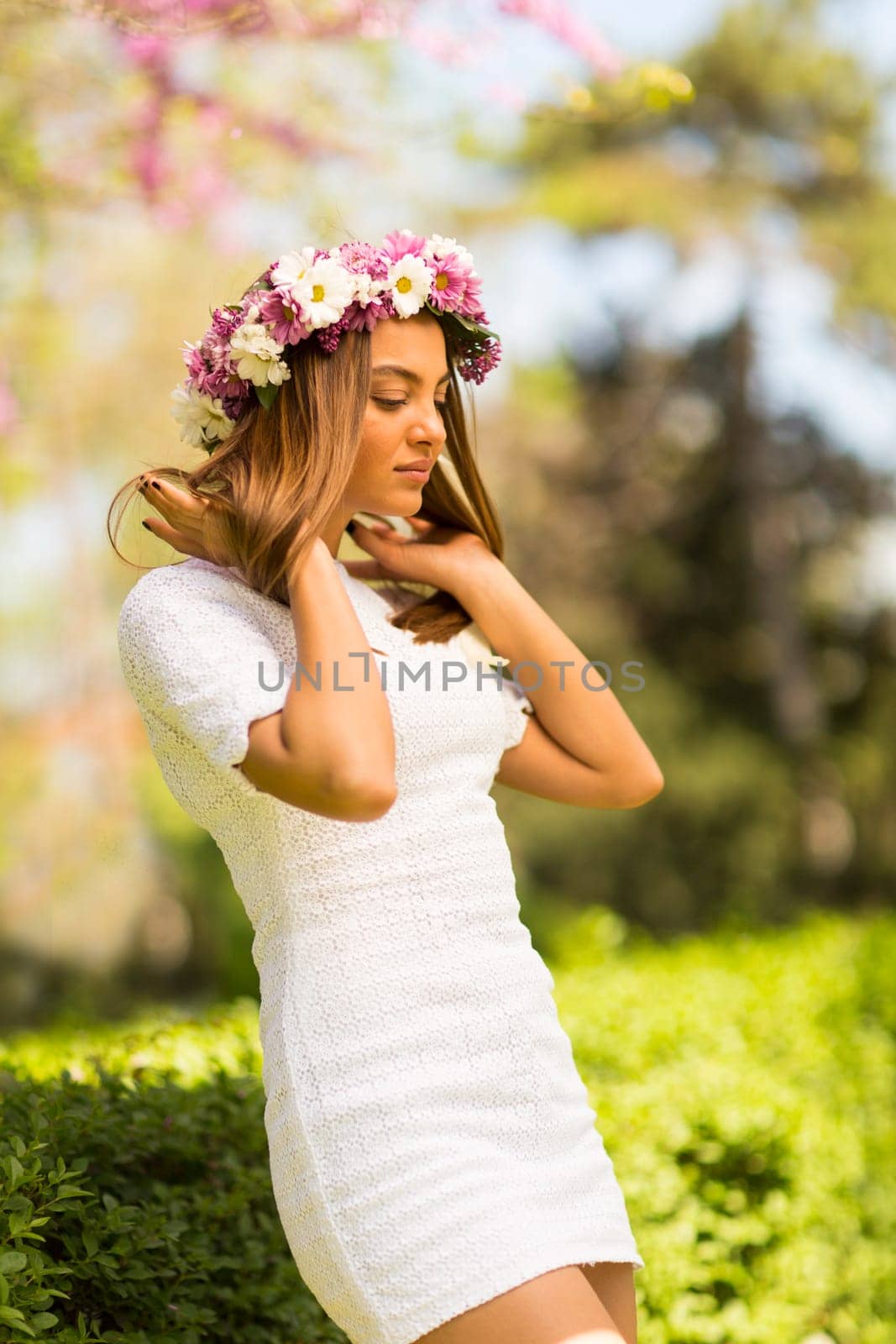 Pretty young woman with flowers in her hair on sunny spring day