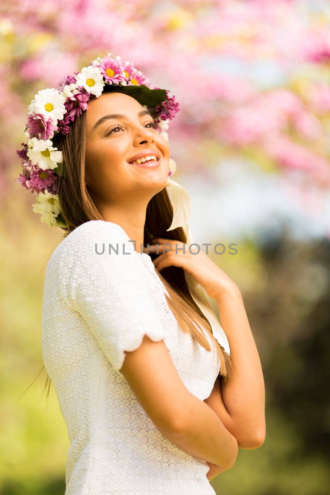 Pretty young woman with flowers in her hair on sunny spring day