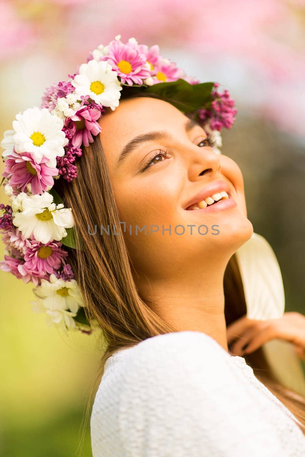 Pretty young woman with flowers in her hair on sunny spring day