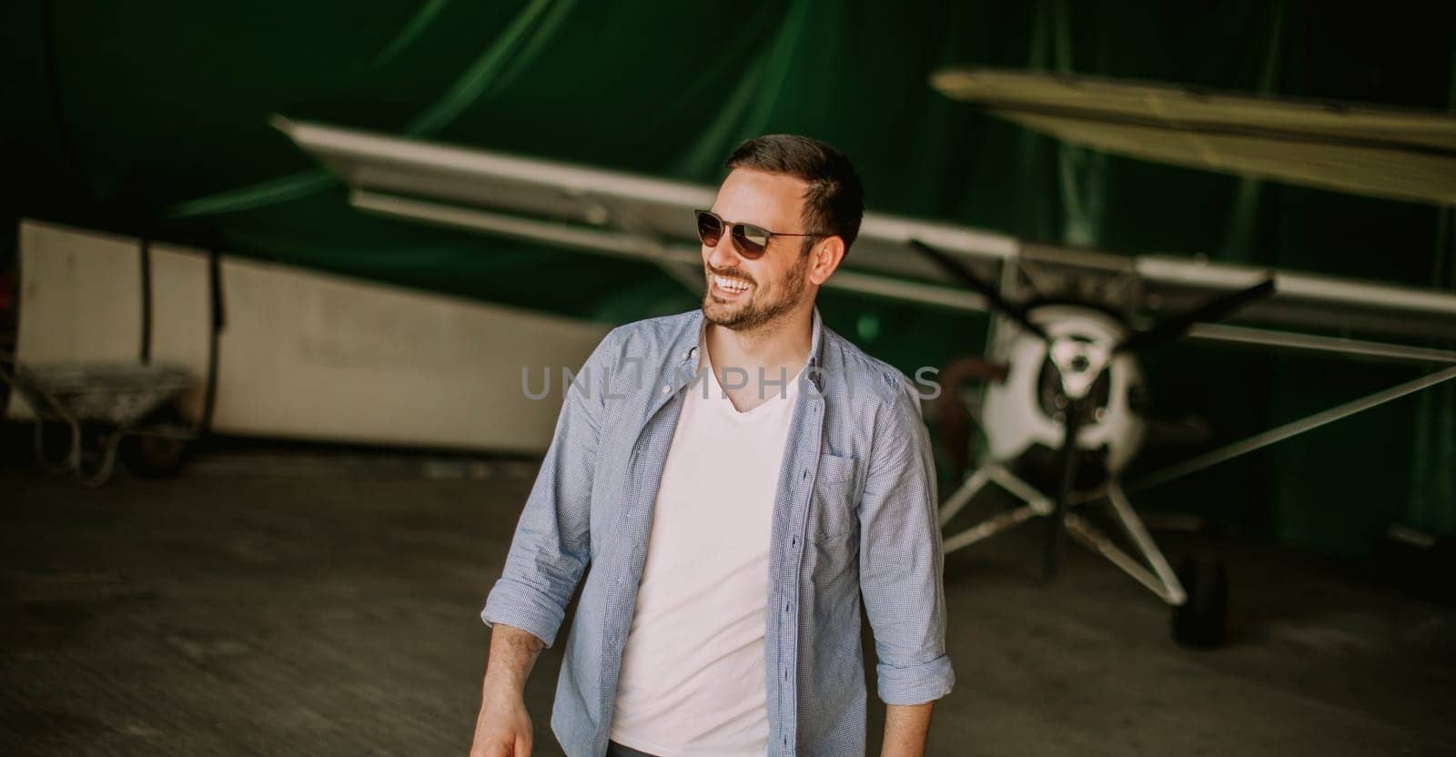 Handsome young pilot checking ultralight airplane before flight