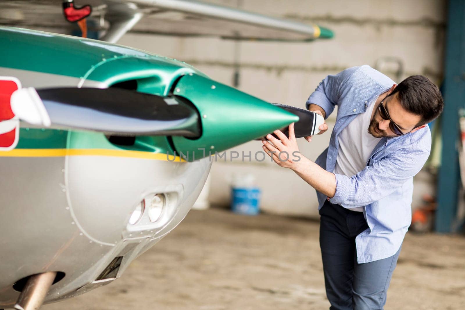 Handsome young pilot checking airplane  in the hangar