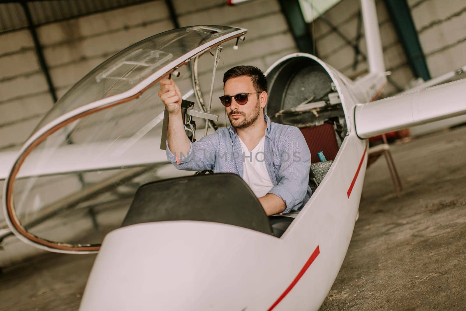 Handsome young pilot checking his ultralight airplane in the hangar before flight