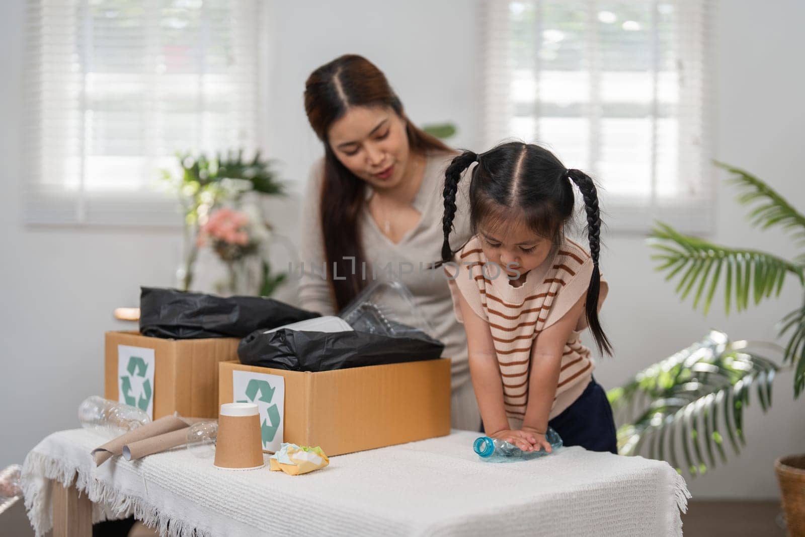 A concerned mother guides her daughter in identifying recyclable materials, teaching valuable lessons about sustainability while bonding over their time together.