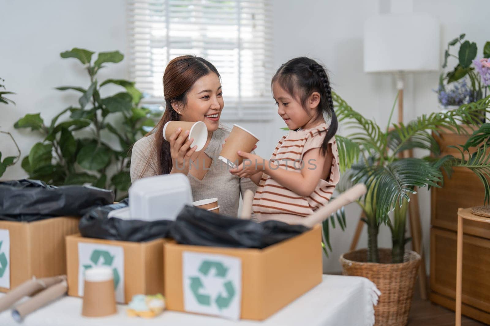 In an inviting atmosphere, a mother and daughter enjoy their time sorting paper cups and discussing the benefits of recycling, promoting a sustainable lifestyle.
