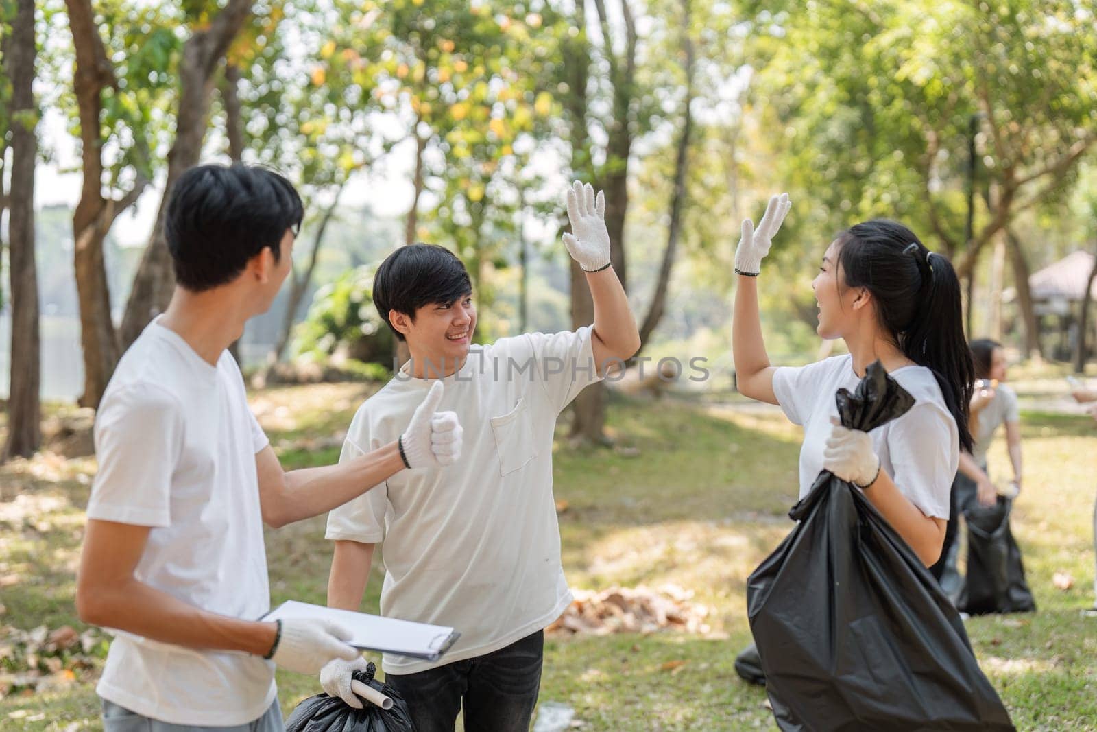 Two young volunteers high-fiving each other, celebrating their teamwork during a community cleanup event focused on sustainability.