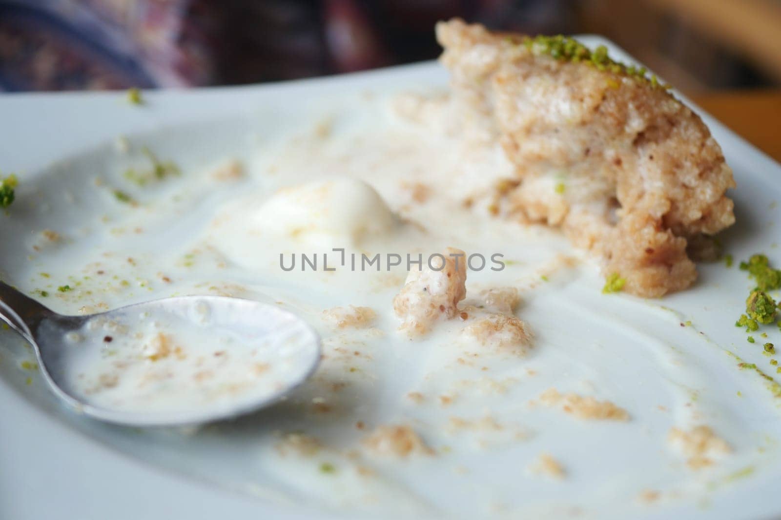 Dessert plate with remnants of a sweet dish and a spoon is shown.
