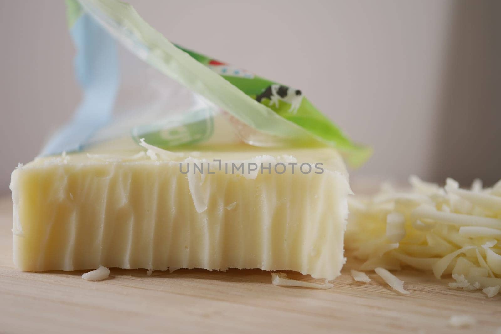 Grated cheese lies next to an unwrapped block on a kitchen counter.