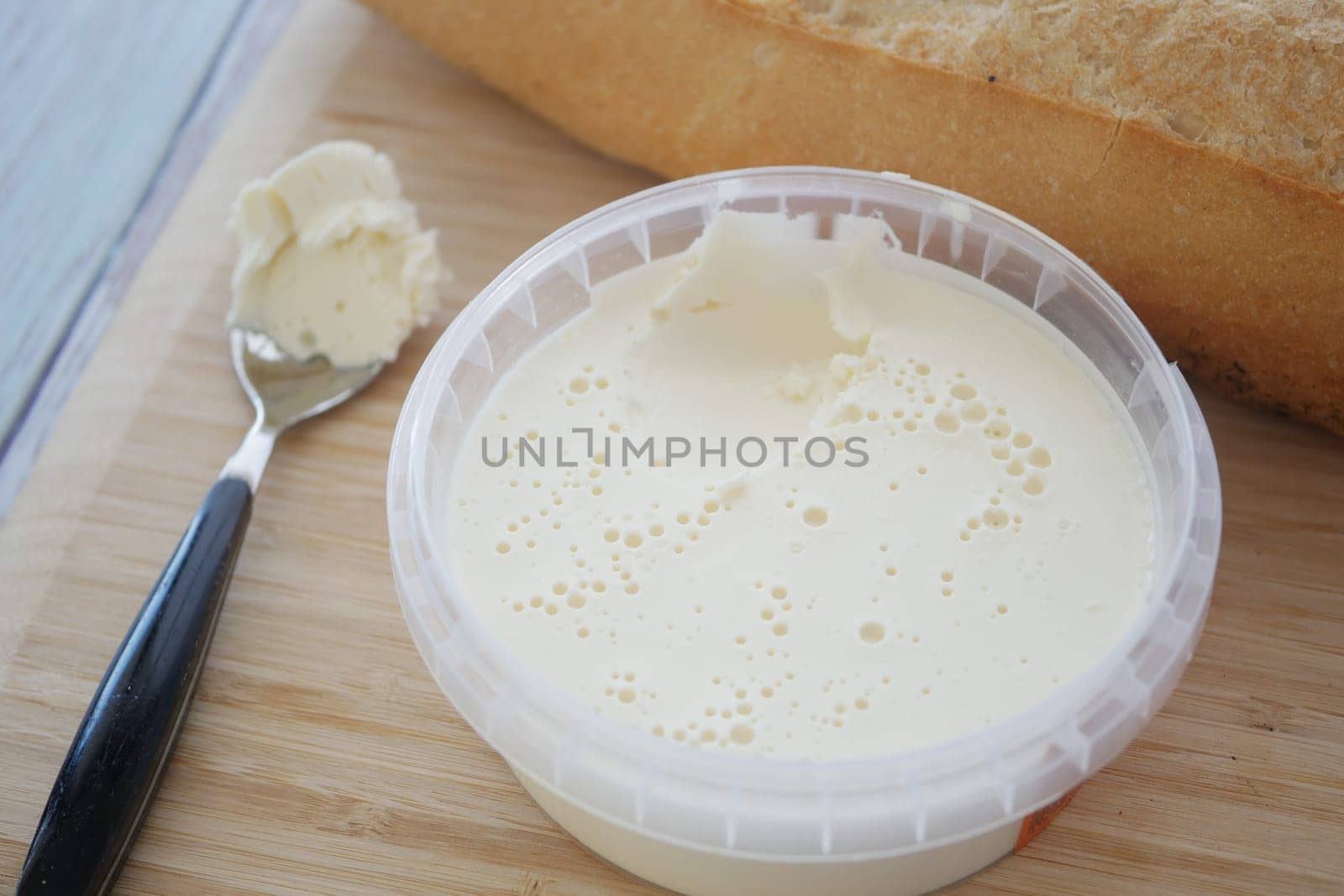 Fresh butter lies near a loaf of bread on a wooden cutting board.
