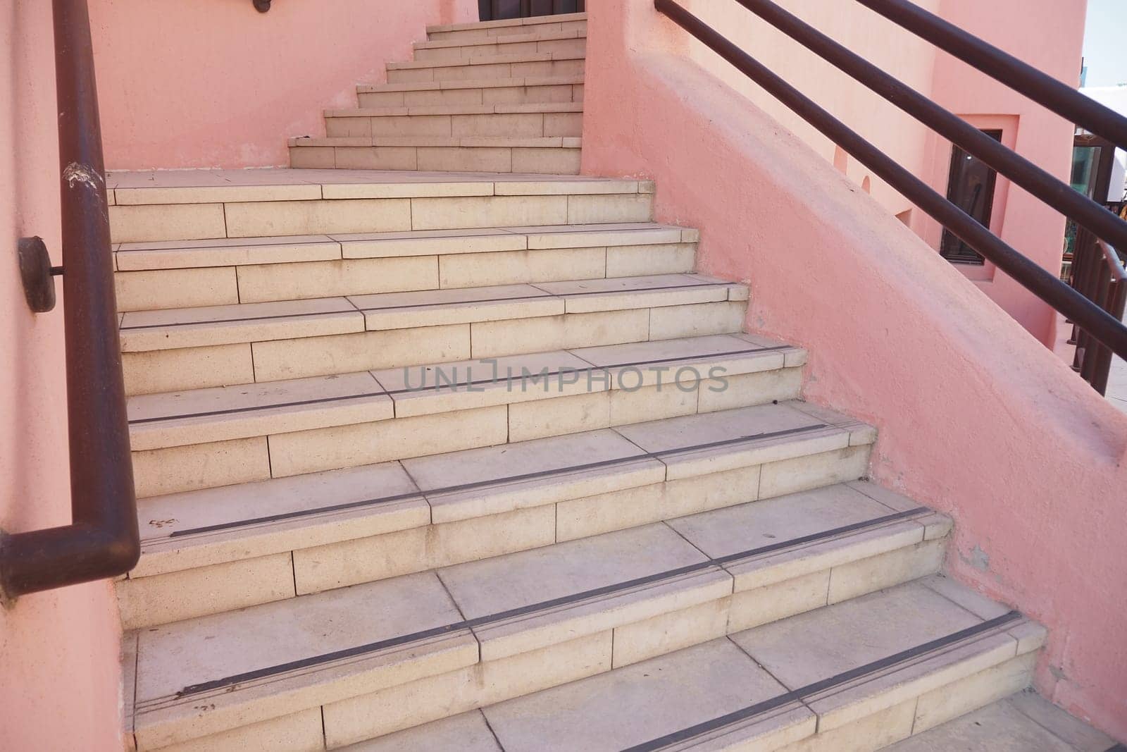 Light-colored stairs ascend towards a colorful building in daylight.