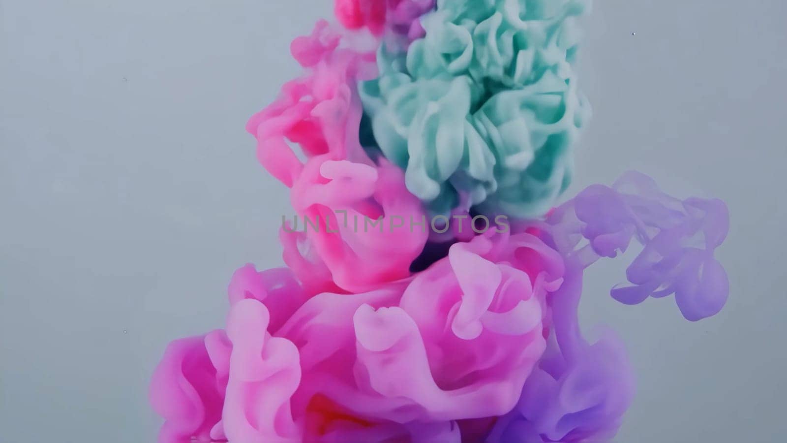 Vibrant hues of pink and teal flow together as ink and liquid paint swirl and mix. This abstract backdrop showcases the beauty of color in fluid motion, creating a stunning visual experience.