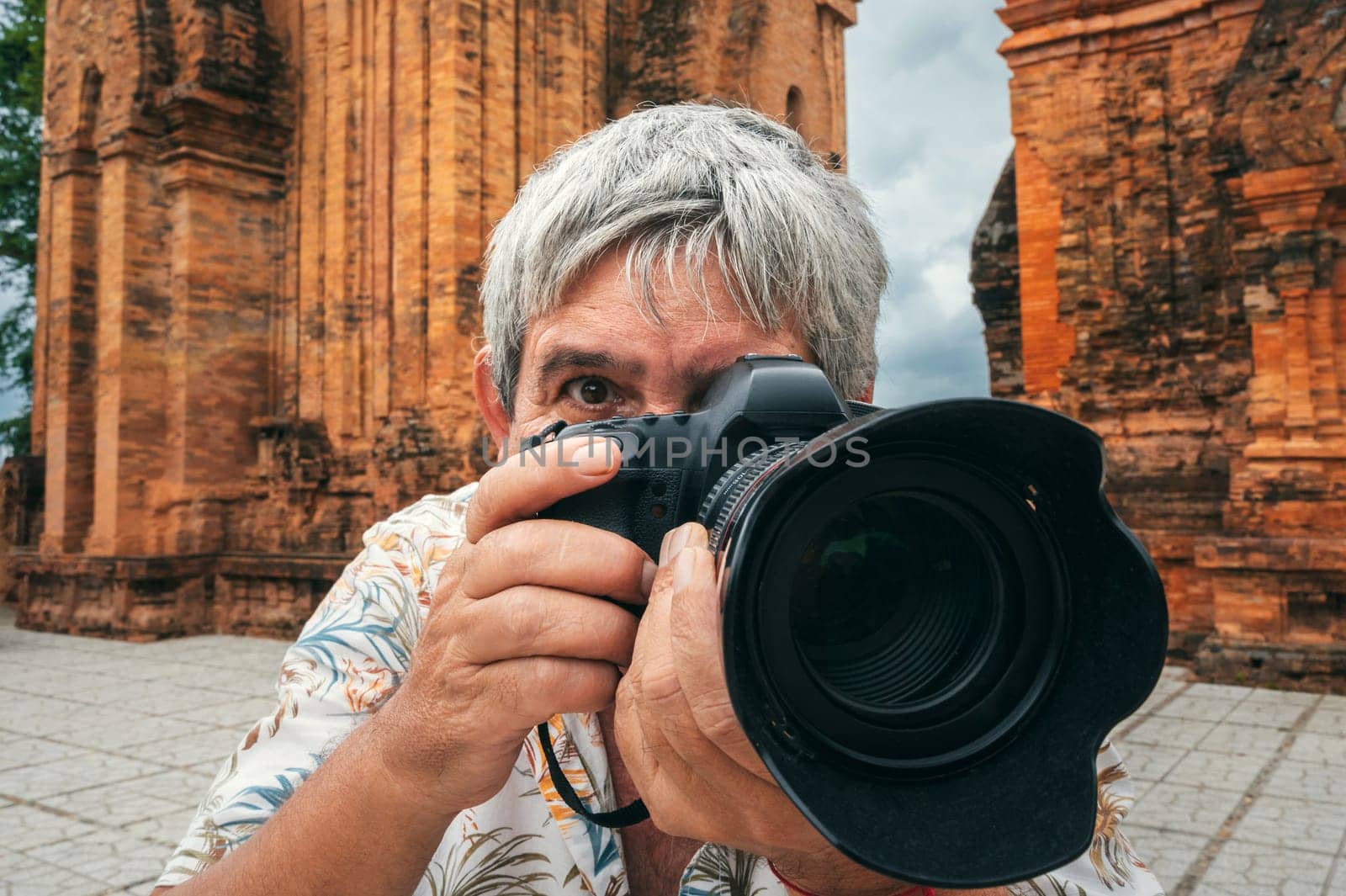 elderly man tourist traveling professional photographer with a camera takes pictures of landmarks at Po Nagar Cham Towers in Nha Trang in Vietnam in Asia