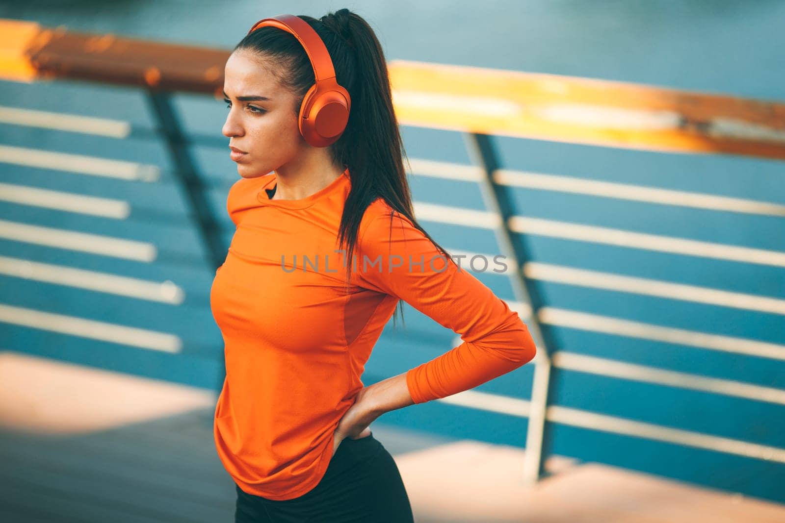 Pretty young woman takes a break after running in urban area