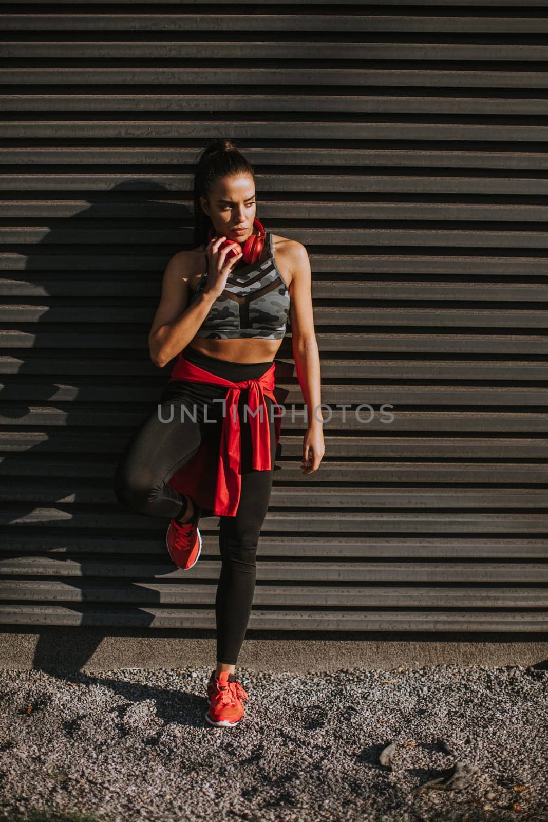 Pretty young woman takes a break after running in the urban area