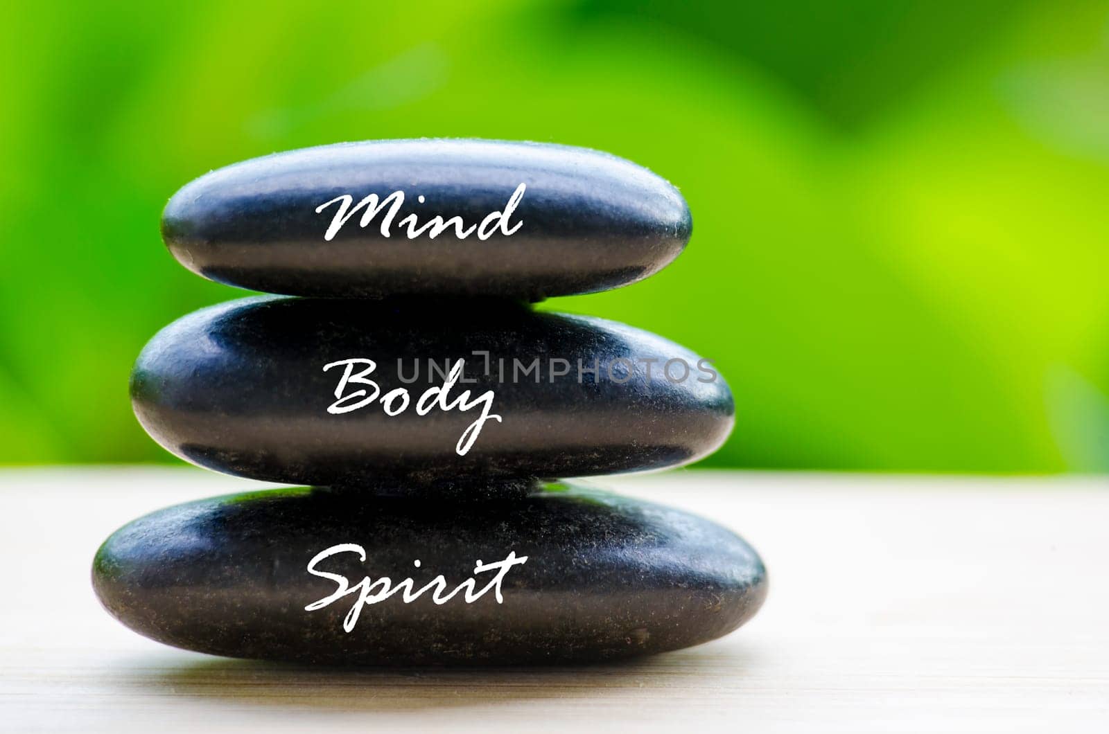 Close up of black Zen stones with Mind Body and Spirit text on the stones. Zen and peaceful concept.