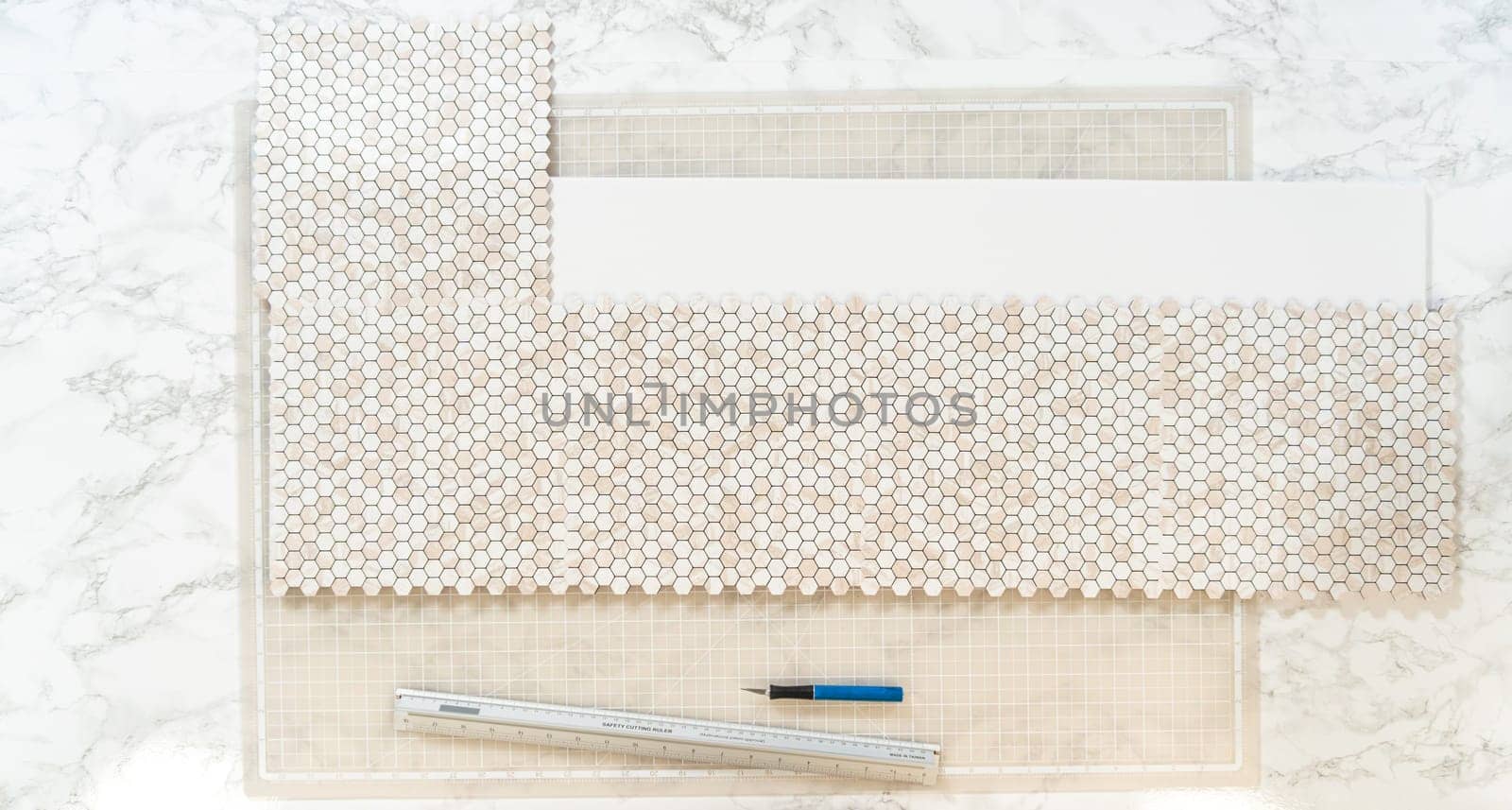 In the process of mounting peel and stick mosaic tiles onto a foam board, perfect for enhancing a food photography studio's aesthetic.