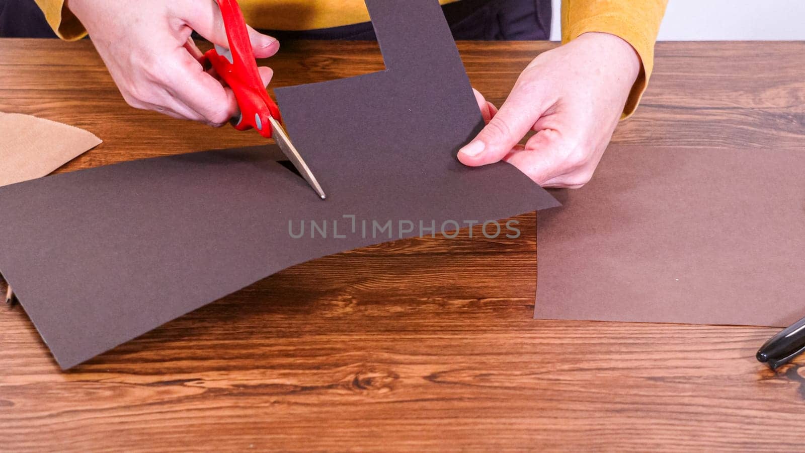 Step by step. Teacher guides online class through making a paper puppet from a brown bag, creatively using a wooden surface as a workspace.
