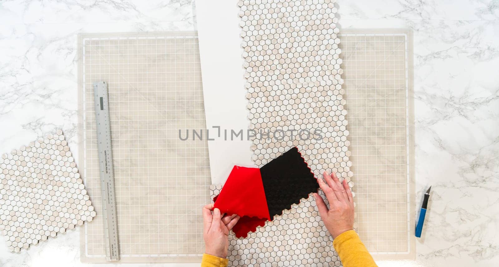 In the process of mounting peel and stick mosaic tiles onto a foam board, perfect for enhancing a food photography studio's aesthetic.