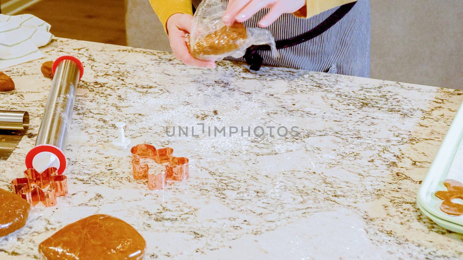 Using an adjustable rolling pin to roll out gingerbread cookie dough on the elegant marble counter in a modern kitchen, getting ready for festive holiday baking.