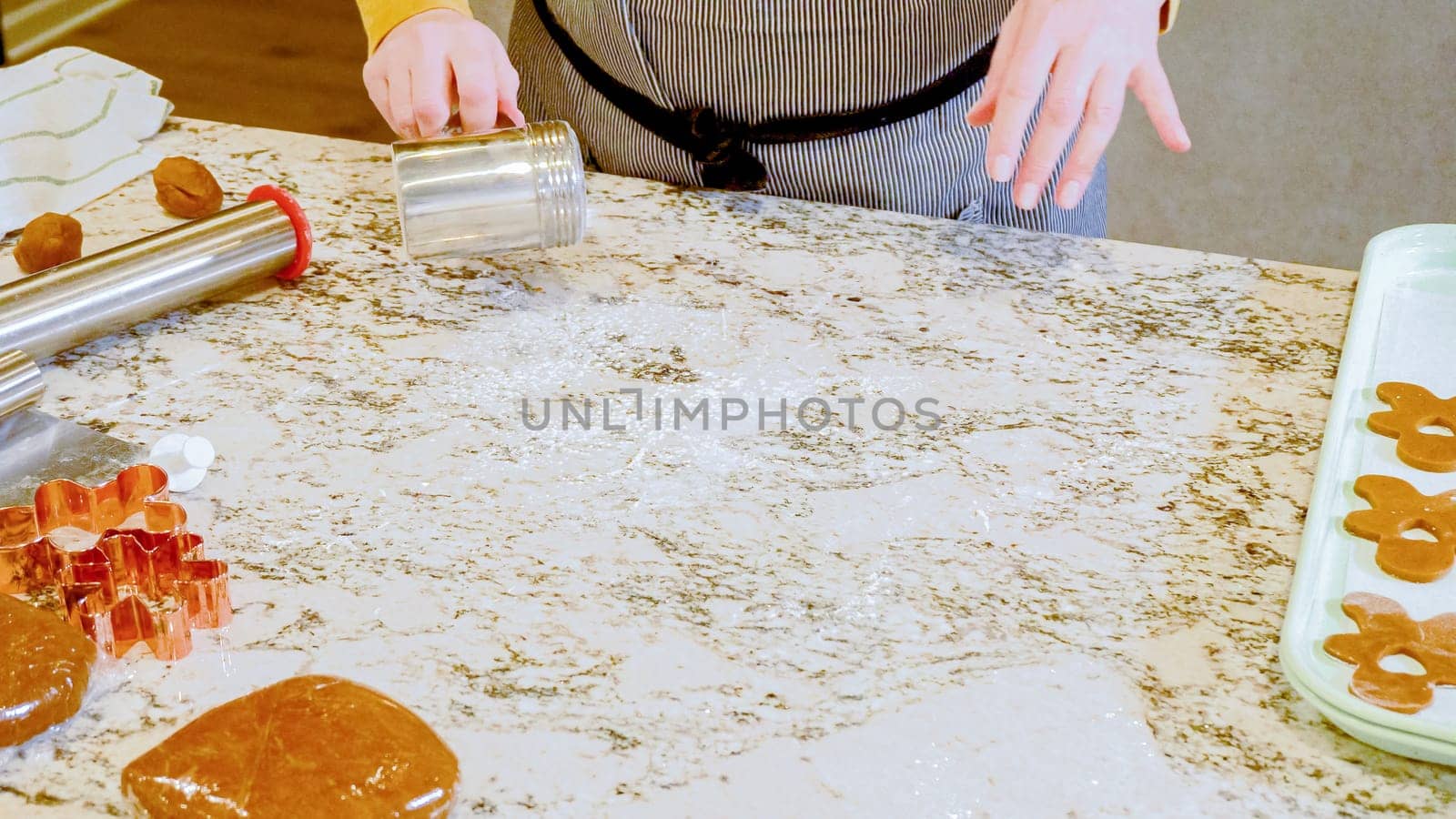 Using an adjustable rolling pin to roll out gingerbread cookie dough on the elegant marble counter in a modern kitchen, getting ready for festive holiday baking.