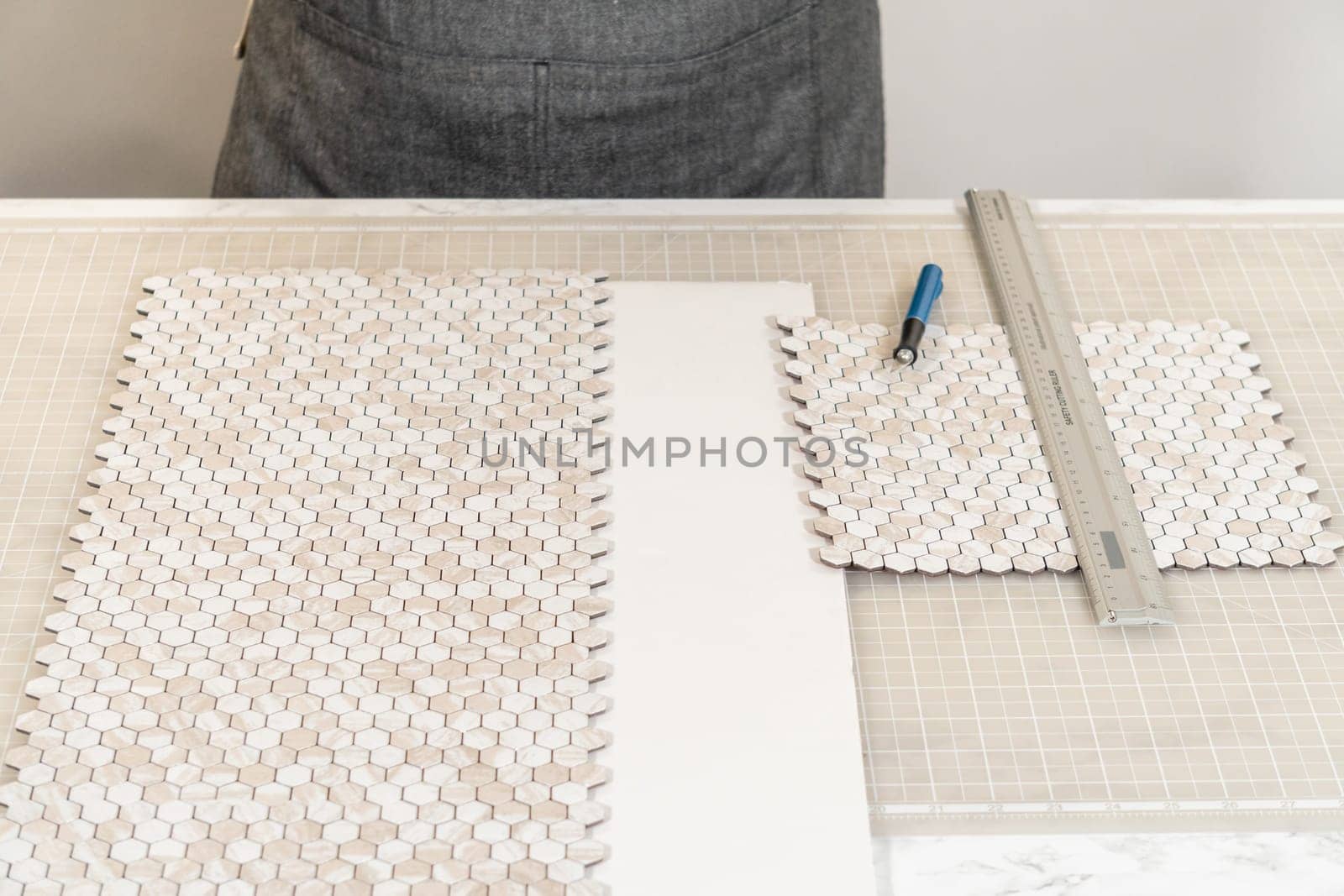 In the process of mounting peel and stick mosaic tiles onto a foam board, perfect for enhancing a food photography studio's aesthetic.