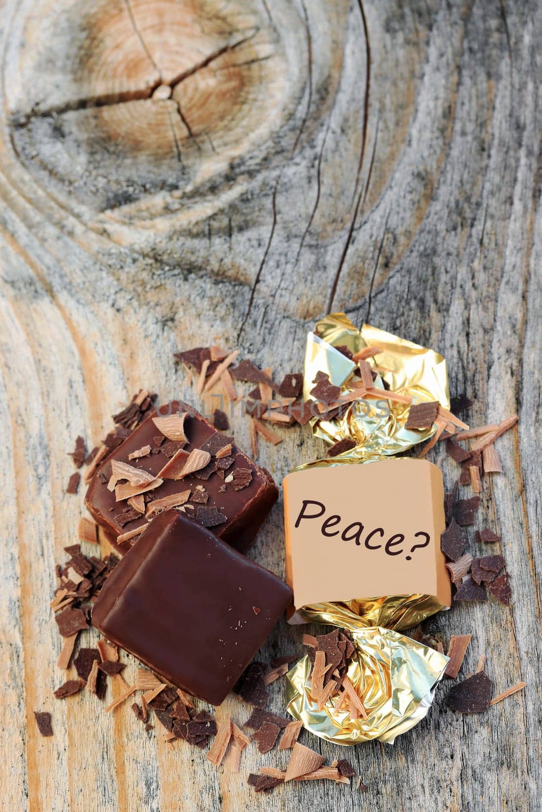 Viereckige Schokoladenpralinen mit Streusel und der Aufschrift Frage Frieden auf einem Holzuntergrund