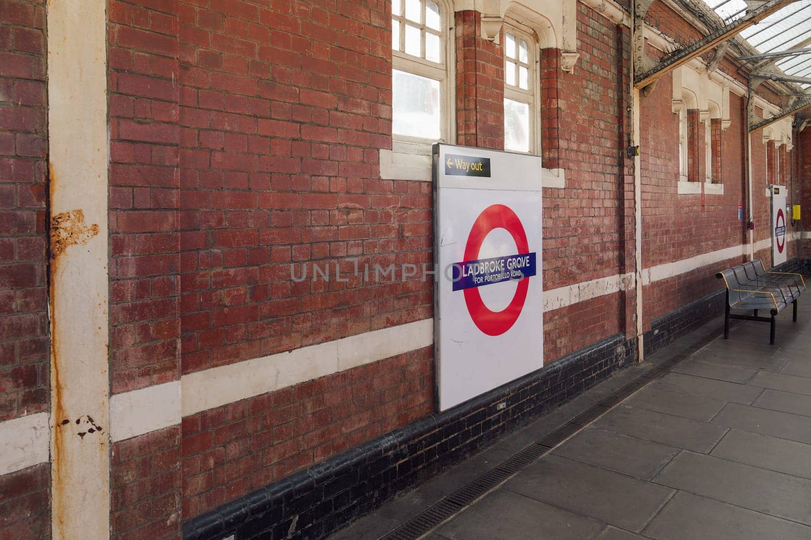 London, UK Ladbroke Grove Tube station empty platform with brick walls, benches and signage.