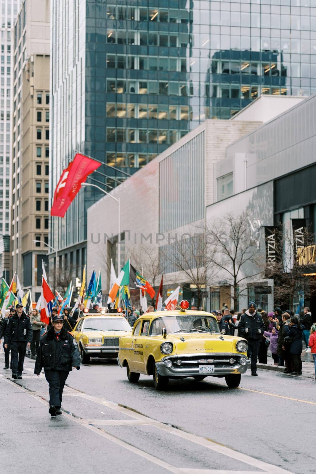 Vibrant city parade showcasing diverse flags and a classic yellow taxi cab.