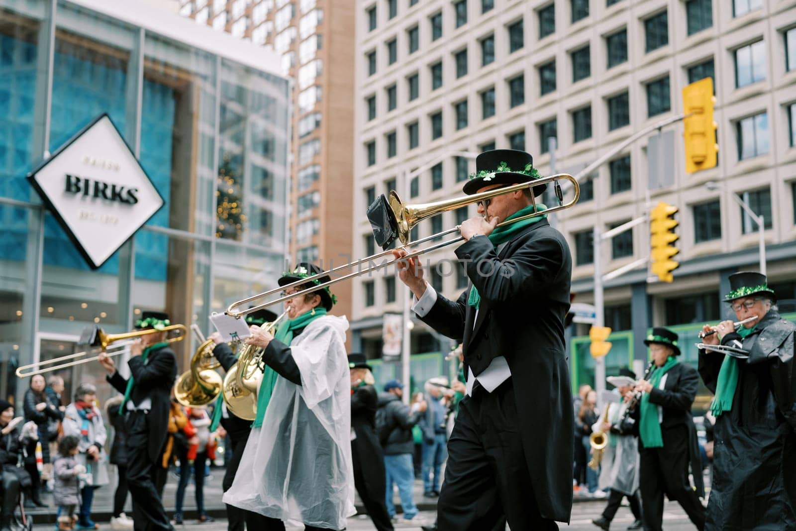 Musicians dressed in colorful costumes are marching in a lively city parade