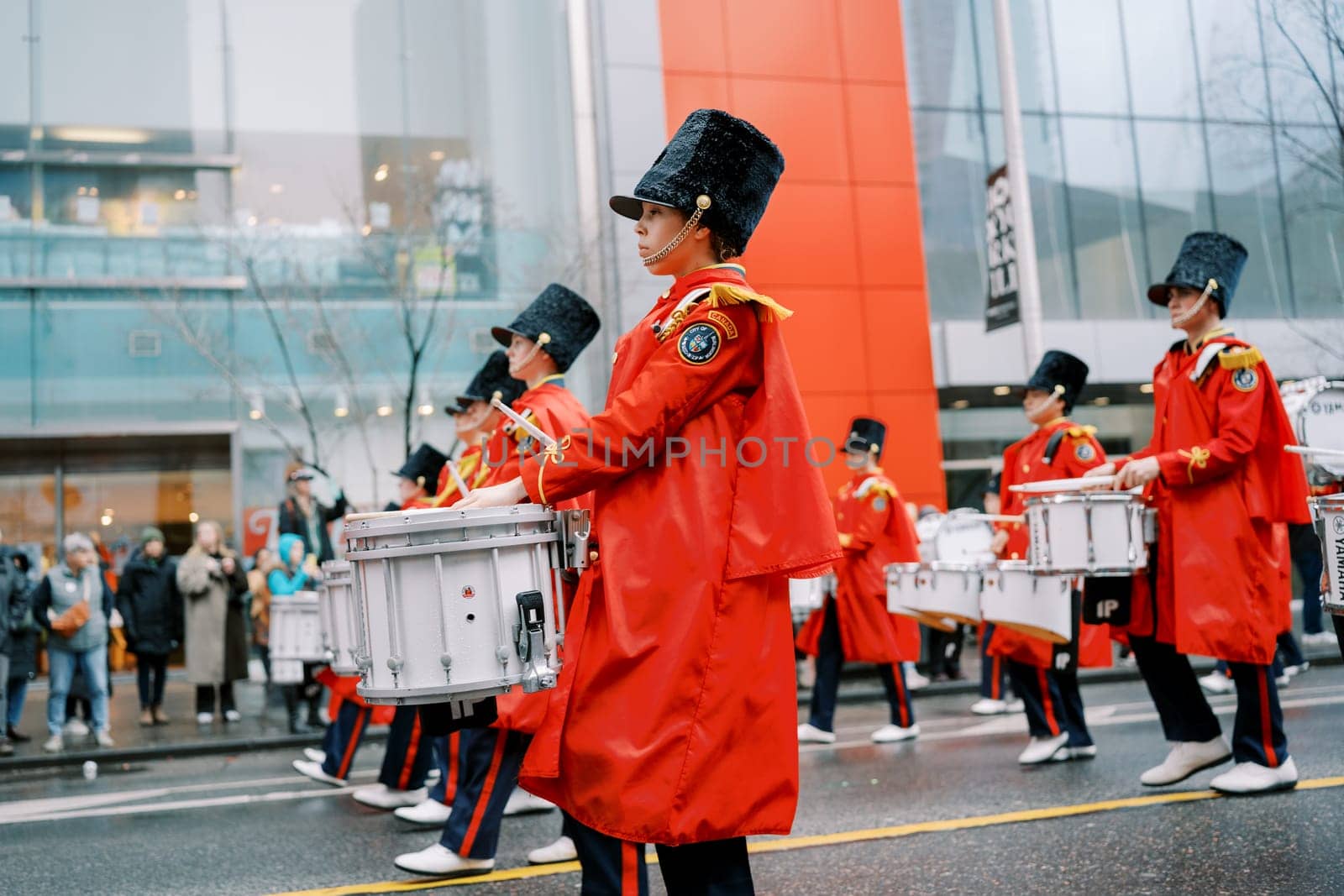 A lively and dynamic parade scene showcasing drummers dressed in vibrant rain gear