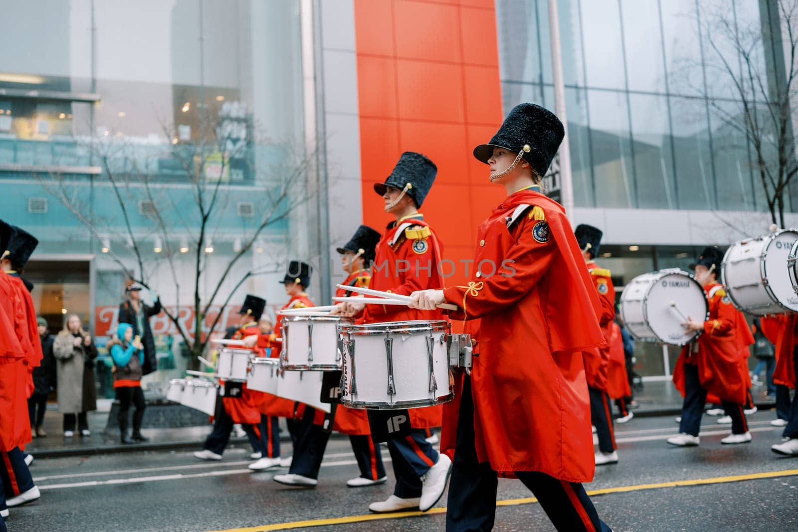 A vibrant and colorful marching band is performing energetically in the city street