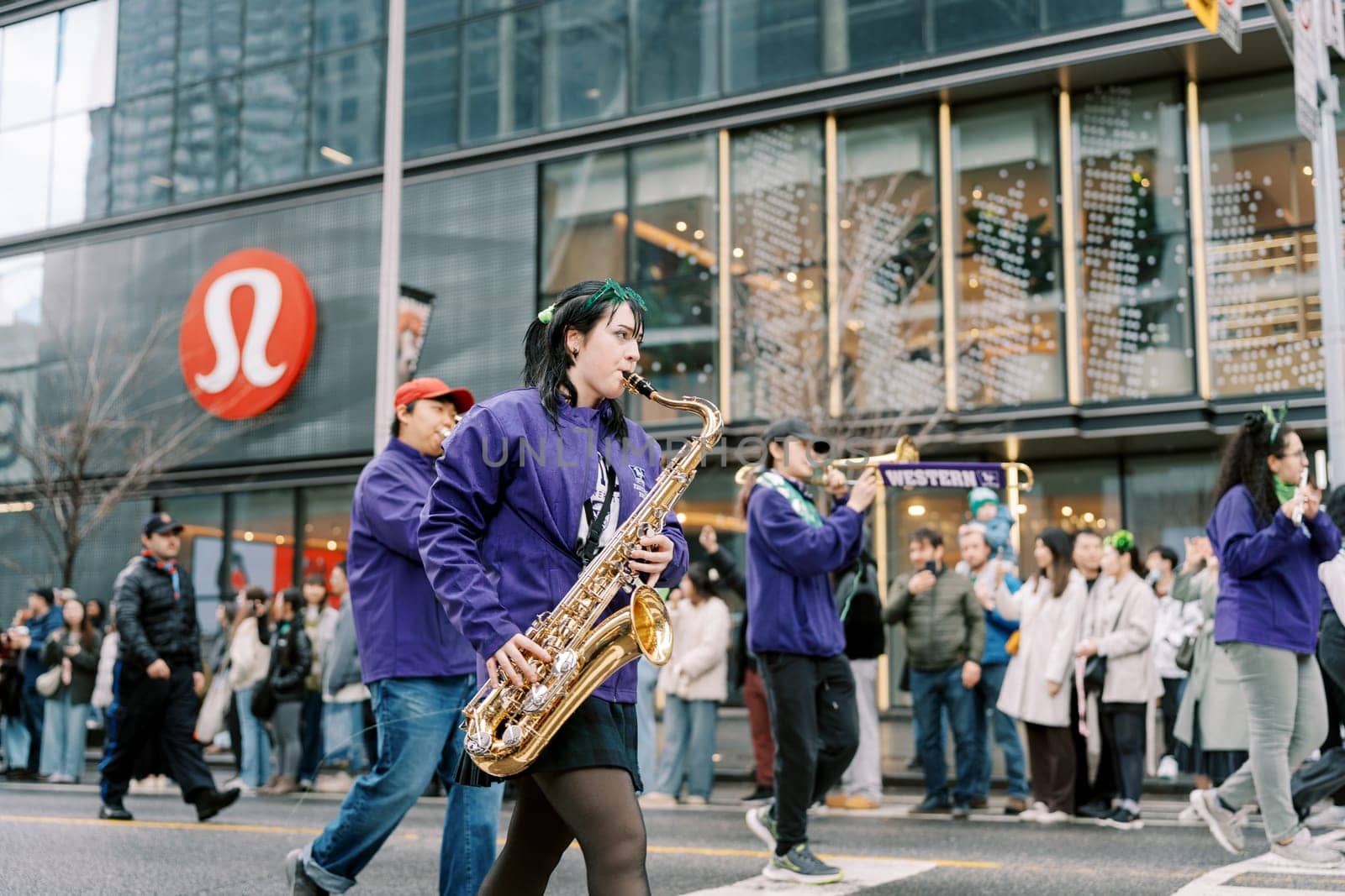 Participants joyfully play instruments in a colorful parade on the city street