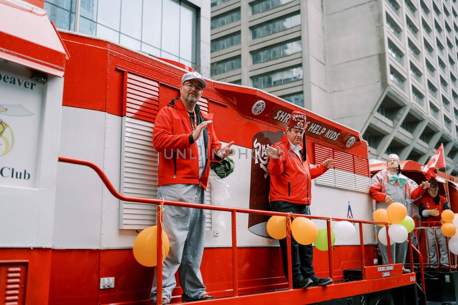 Excited individuals on a colorful parade float engaging with the crowd.