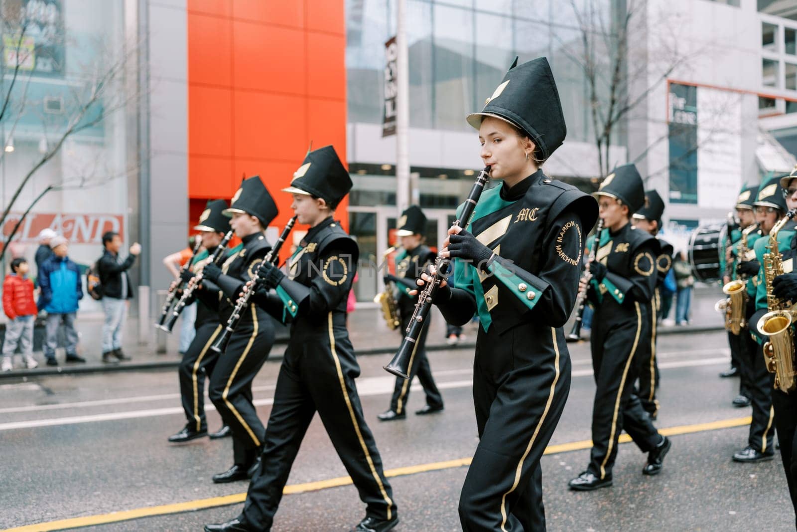 Young musicians in formal attire are joyfully playing instruments at a lively parade