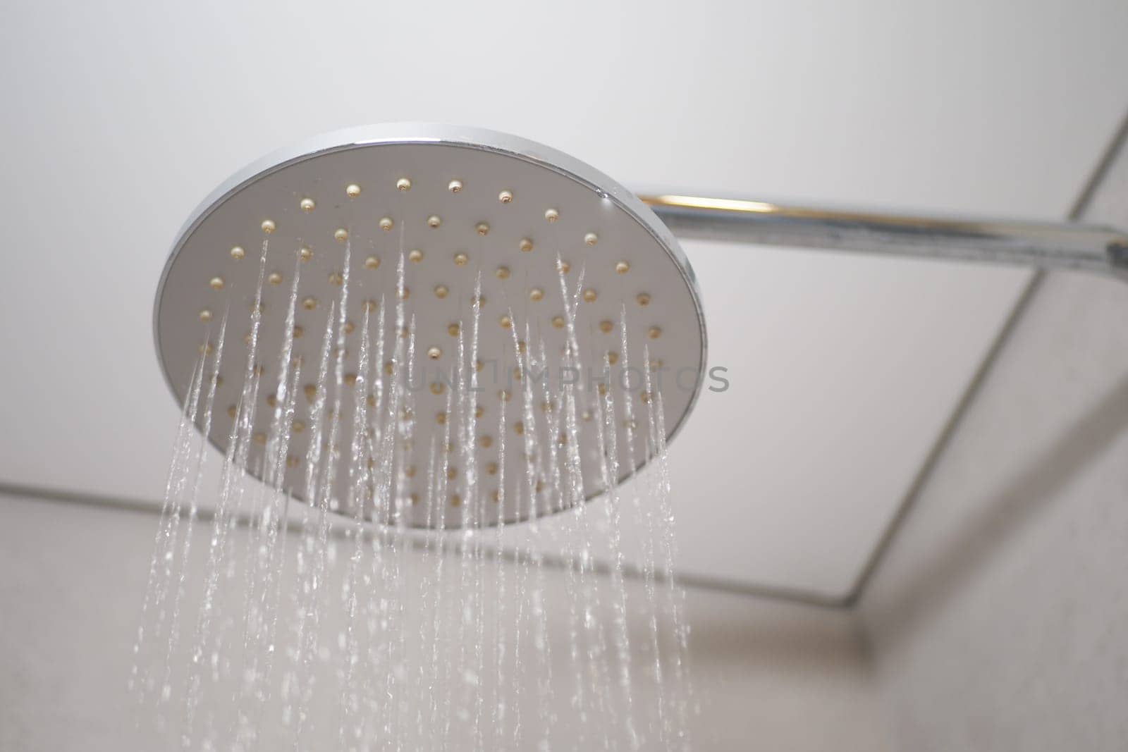 Water flows from a sleek shower head in a contemporary bathroom setting.