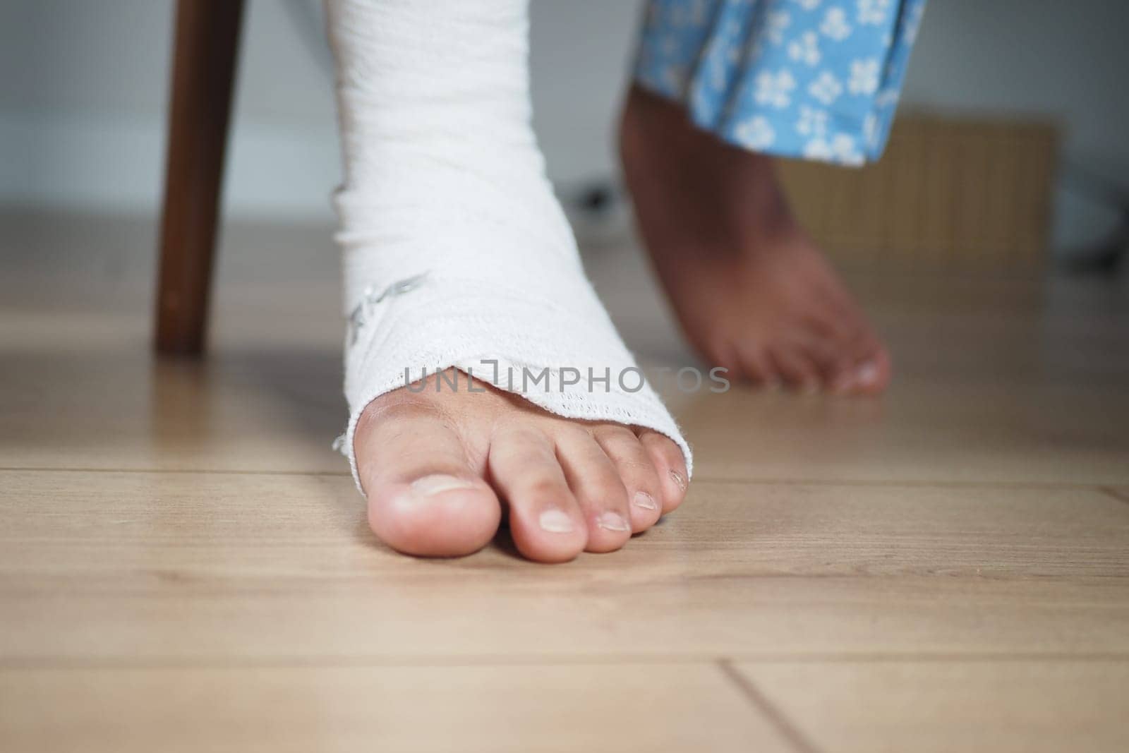 A bandaged foot hovers above a wooden floor, indicating healing progress.