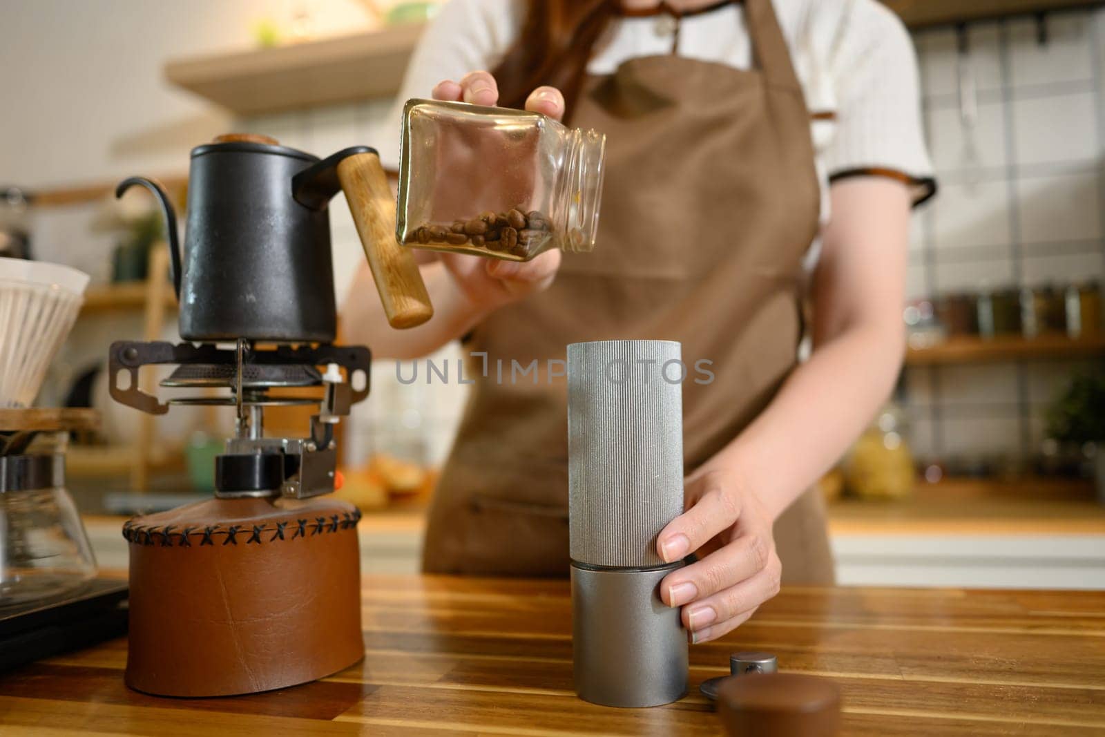 Young woman grinds coffee beans and sets up a brewing station in a modern kitchen.