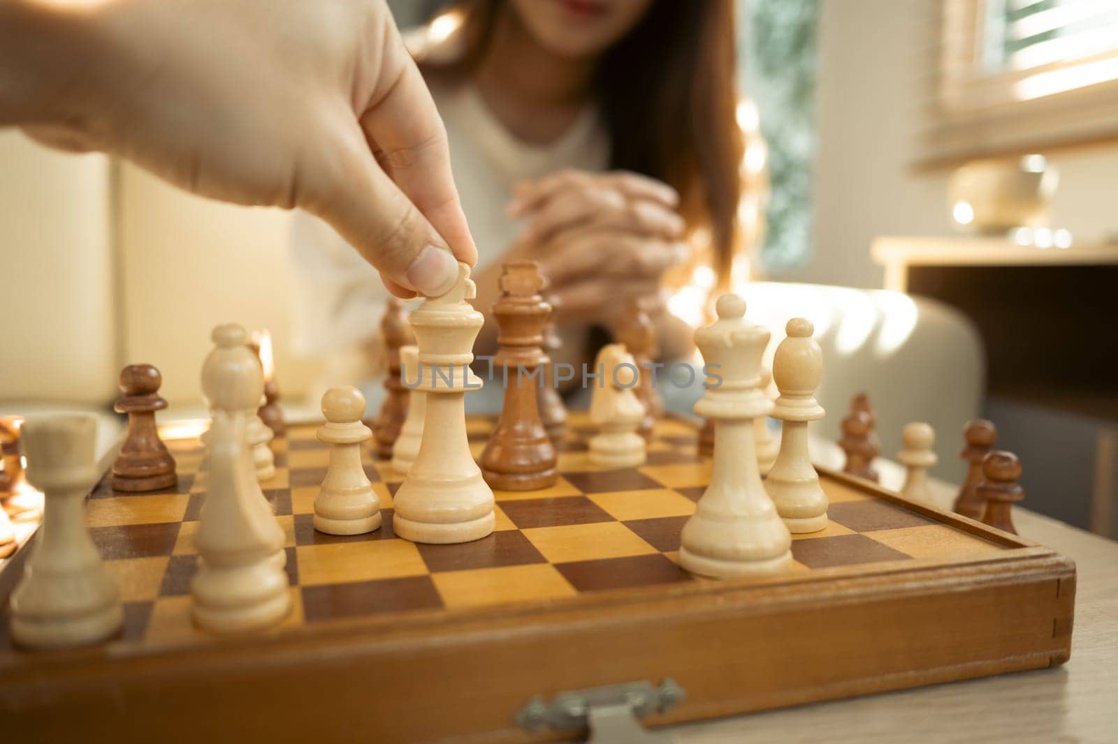 Close up of hand moves a chess piece on a classic wooden chessboard.
