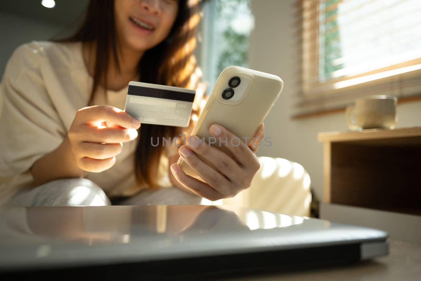 Happy young woman making an online purchase using her mobile phone and credit card.